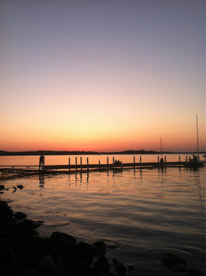 photo of a pier extending into a lake at sunset